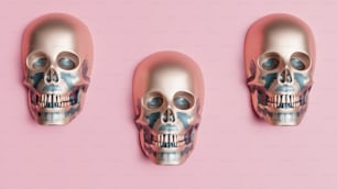 ピンクの背景に3つの銀色の頭蓋骨