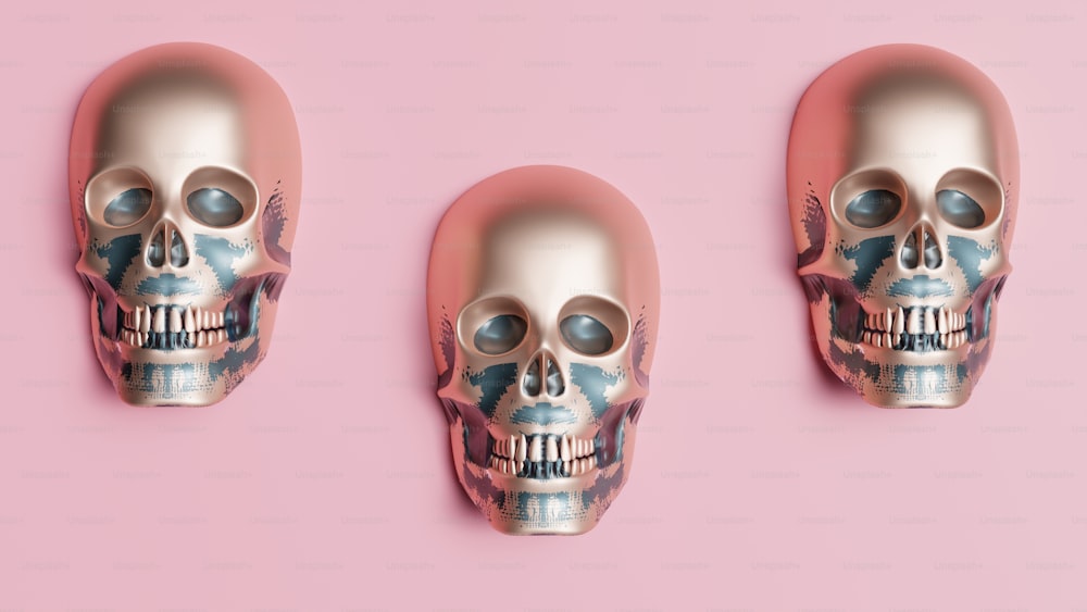 three silver skulls on a pink background