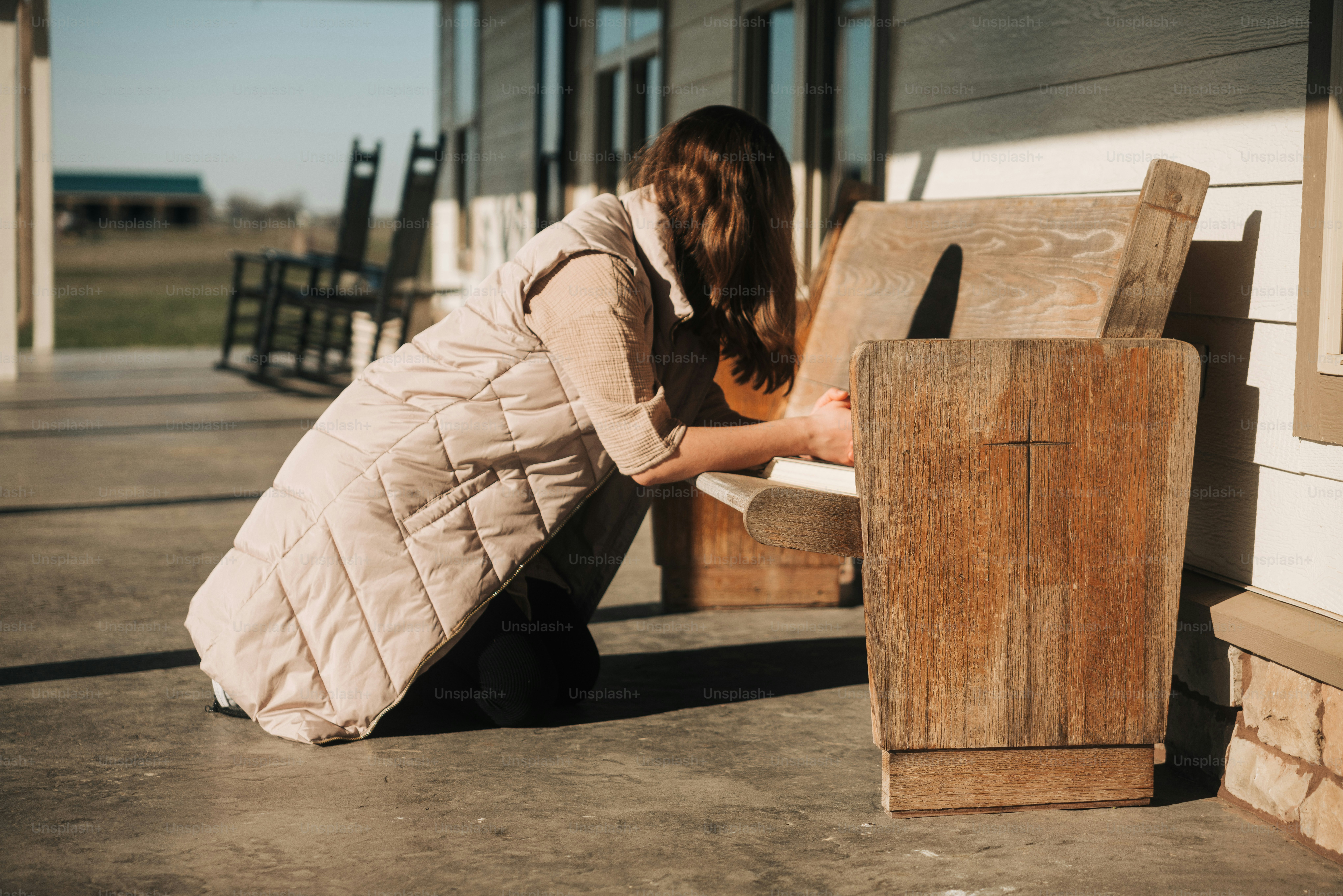 a woman kneeling down next to a wooden bench