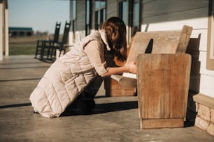 a woman kneeling down next to a wooden bench