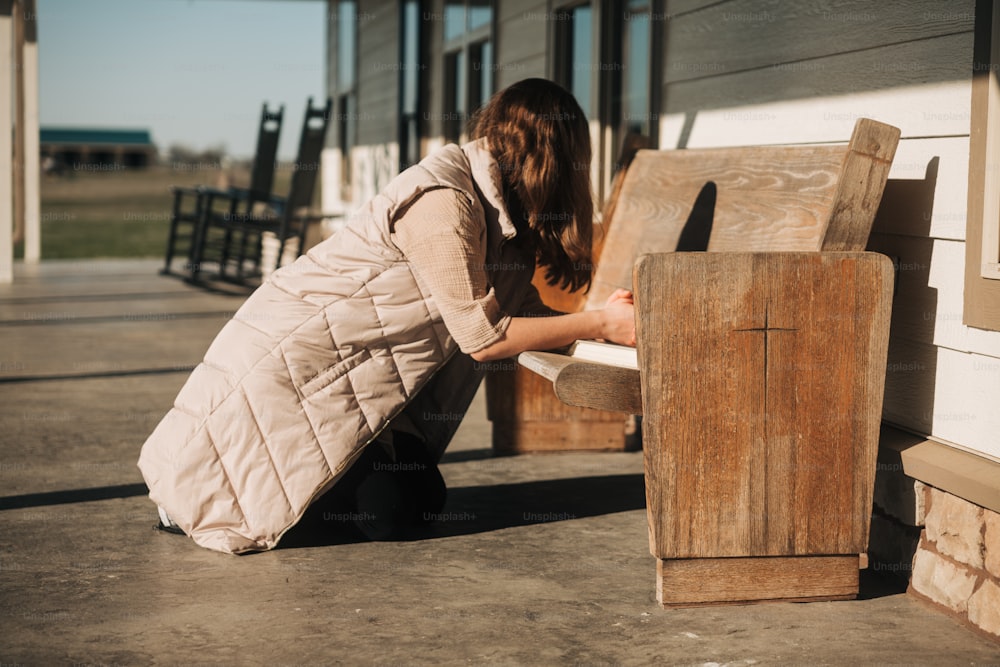 uma mulher ajoelhada ao lado de um banco de madeira