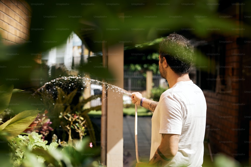 a man in a white t - shirt is spraying water from a hose