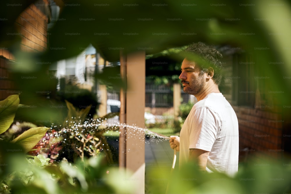 um homem está regando suas plantas no jardim