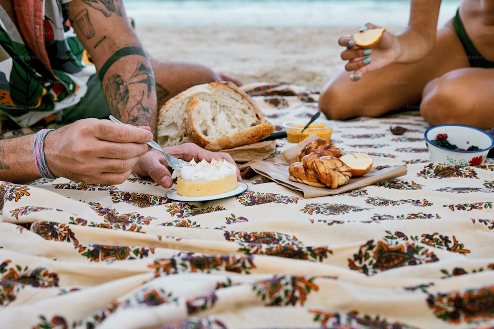Un par de personas sentadas en una playa comiendo comida