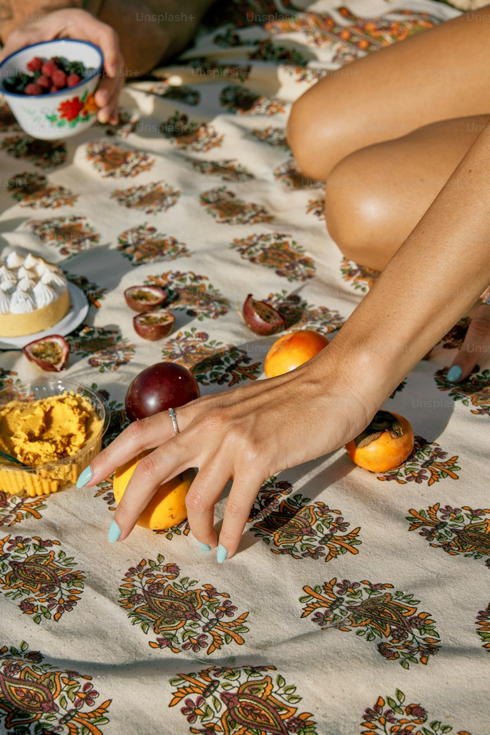 uma mulher sentada em uma cama com uma tigela de frutas