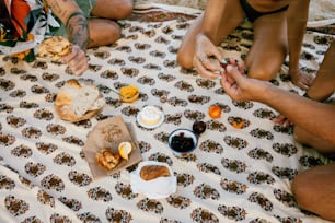 Eine Gruppe von Menschen, die um einen Tisch mit Essen darauf sitzen