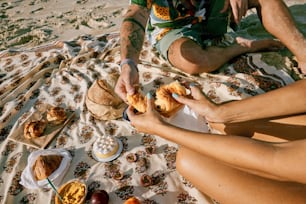 a man and a woman sitting on a blanket on the beach