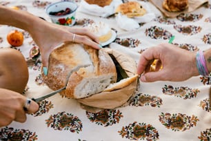 a person cutting a loaf of bread on top of a table