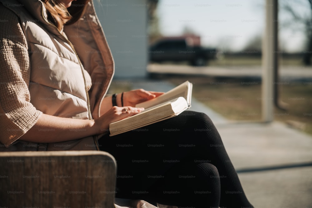 a woman sitting on a bench writing on a book