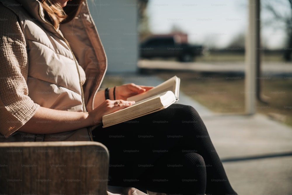 Una mujer sentada en un banco escribiendo en un libro