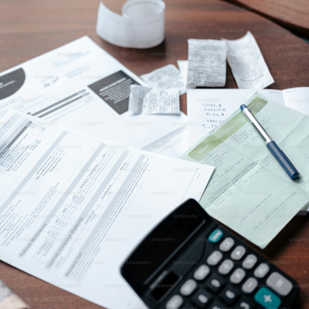 a desk with a calculator, pen and papers on it