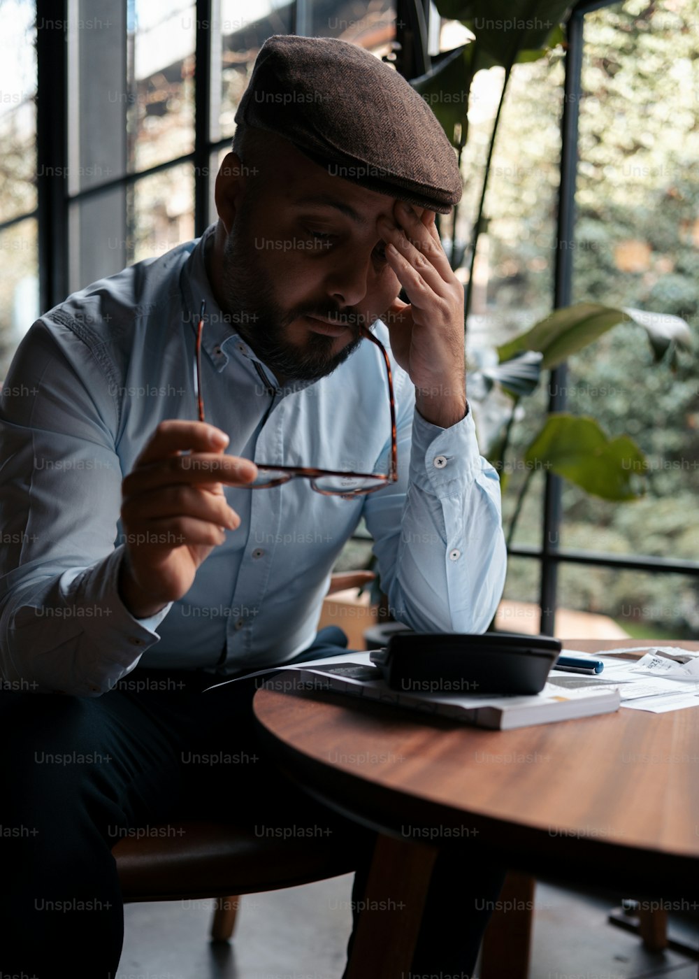 a man sitting at a table holding his head in his hands