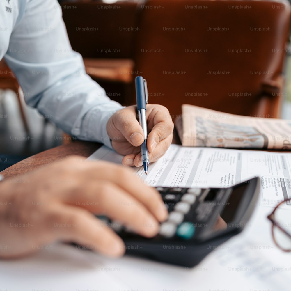 Una persona sentada en una mesa con una calculadora y un bolígrafo