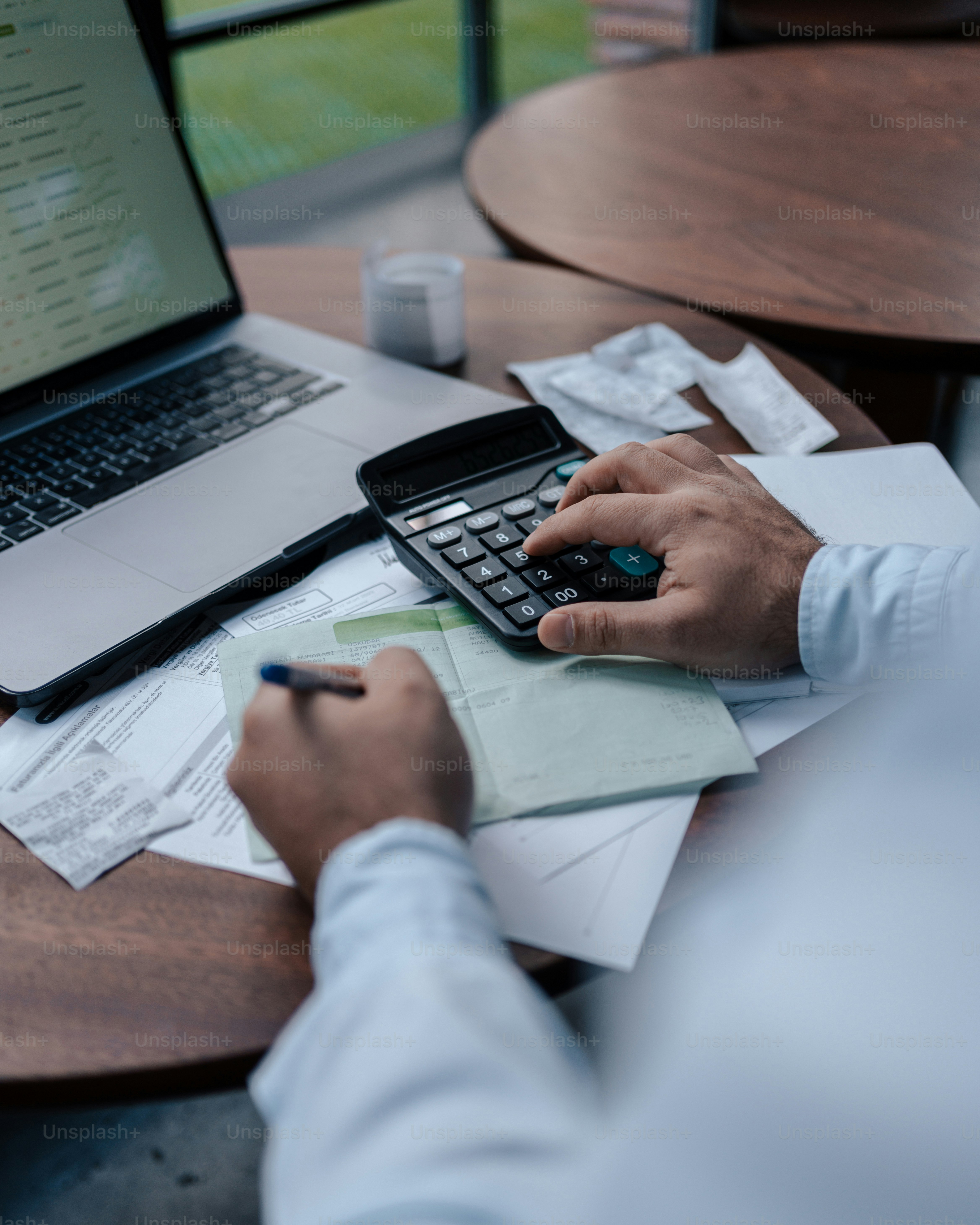 a person sitting at a table with a calculator and a laptop