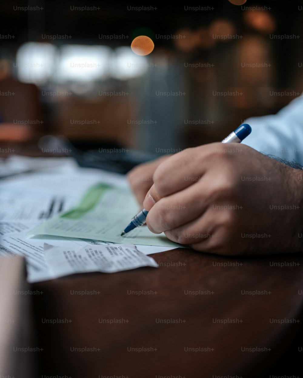 a person sitting at a table with papers and a pen