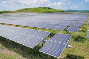 rows of solar panels in a field with mountains in the background