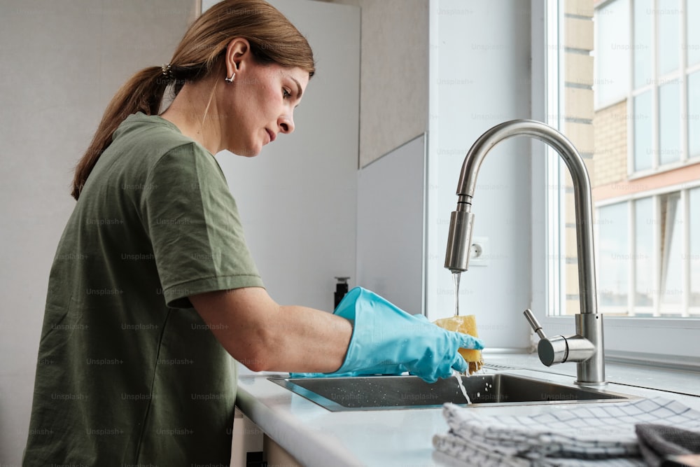 a woman washing dishes in a kitchen sink