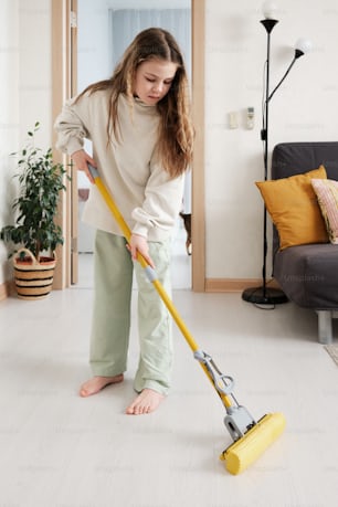 a woman is cleaning the floor with a mop