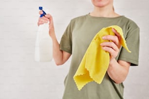 a person holding a cloth and a bottle of cleaner