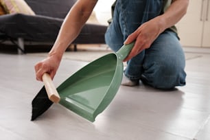 a person kneeling on the floor with a shovel