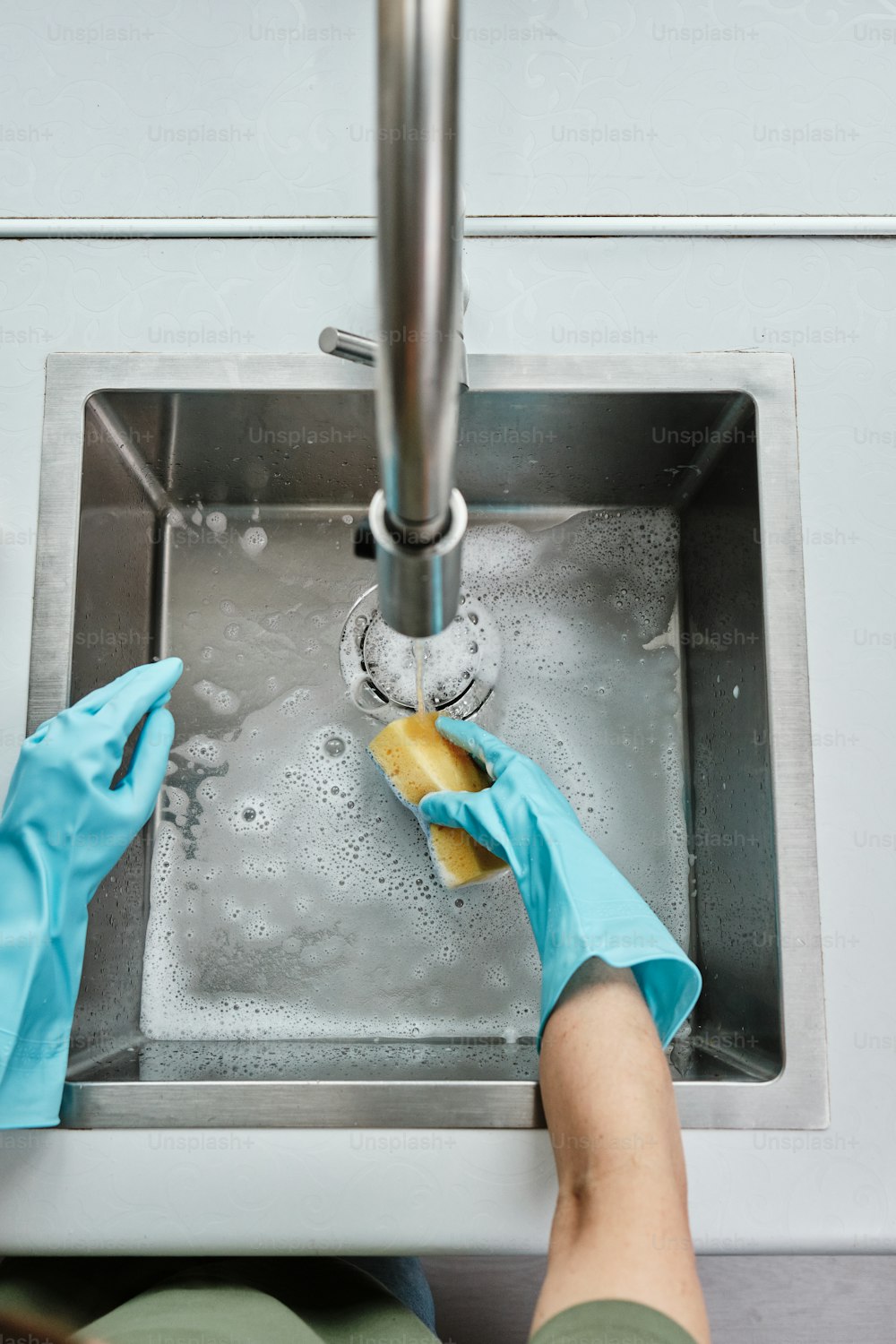 Una persona con guantes azules limpiando un fregadero