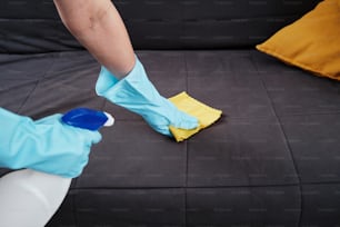 a person in blue gloves and rubber gloves cleaning a couch