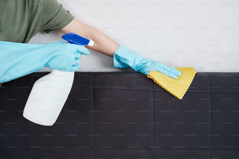 Eine Person in blauen Handschuhen und Gummihandschuhen reinigt eine Matratze