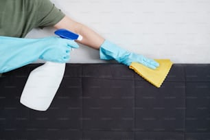 a person in blue gloves and rubber gloves cleaning a mattress