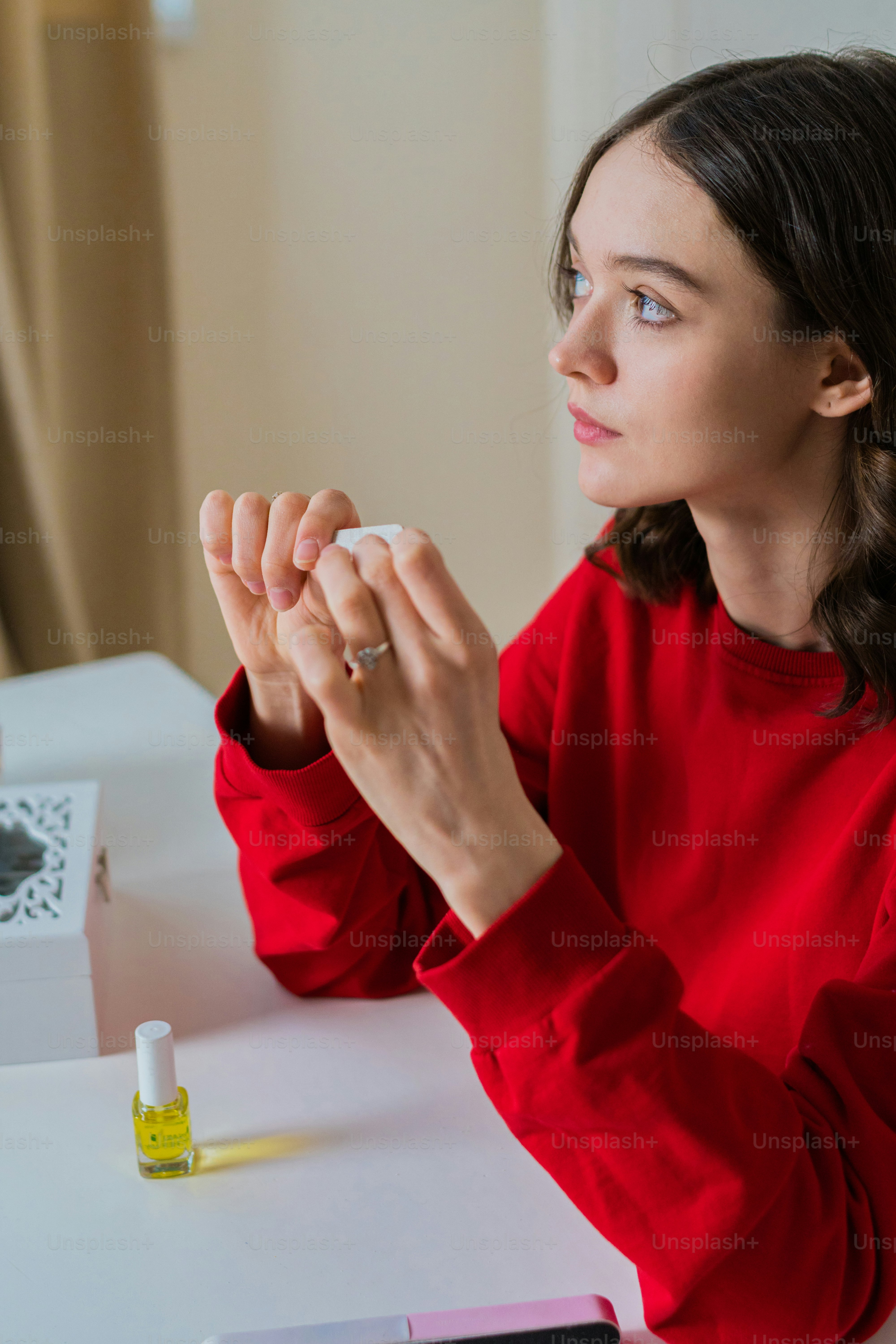 une femme assise à une table, les mains jointes