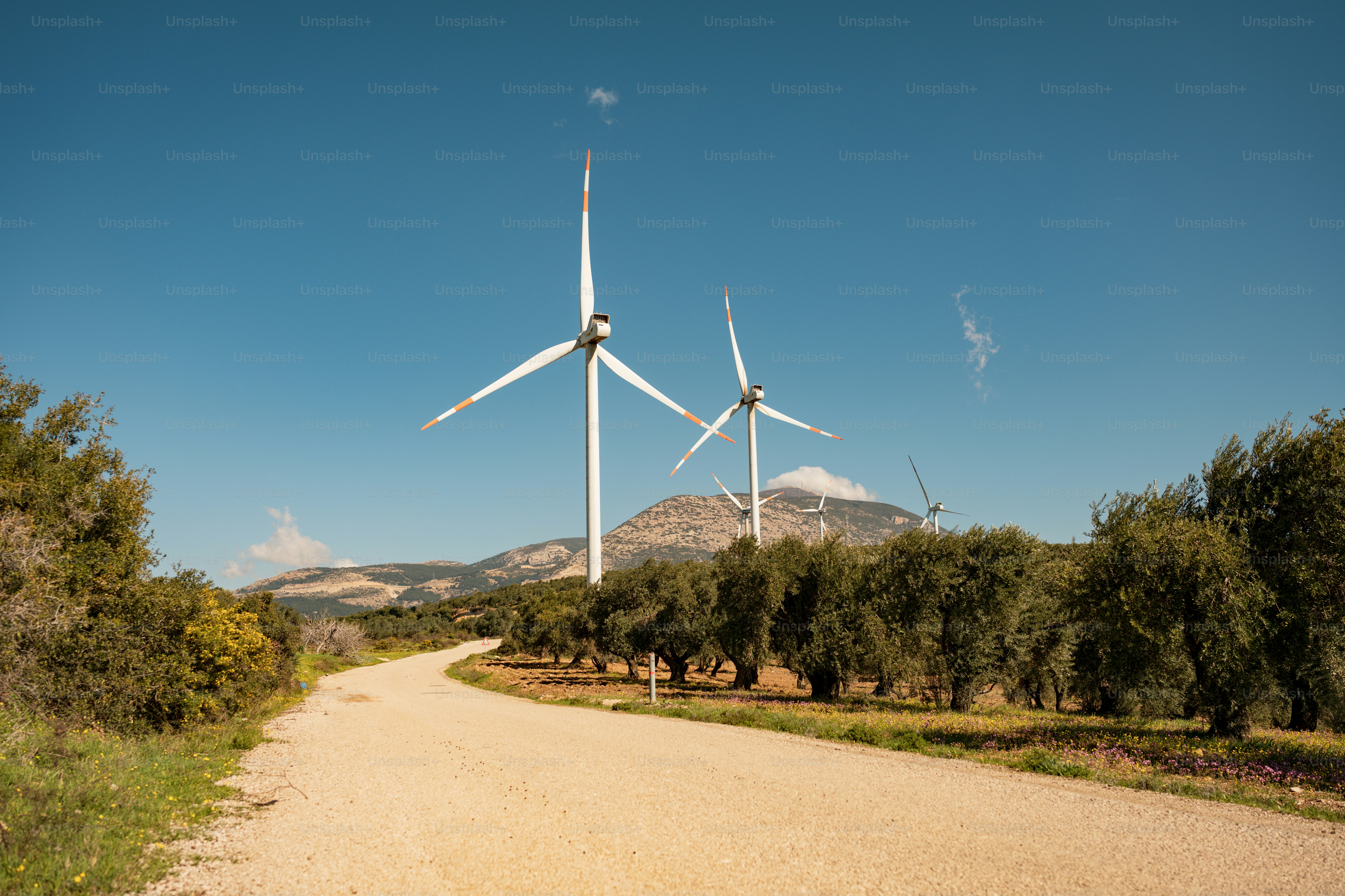 a dirt road with three wind turbines on top of it