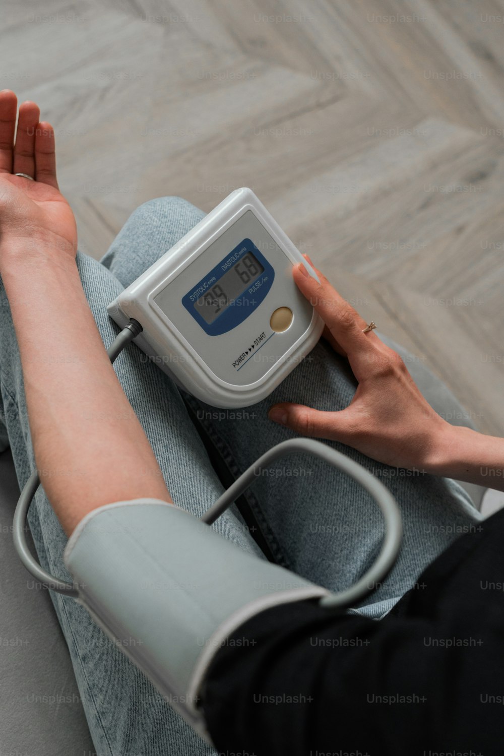 a person sitting on the floor with a blood pressure meter