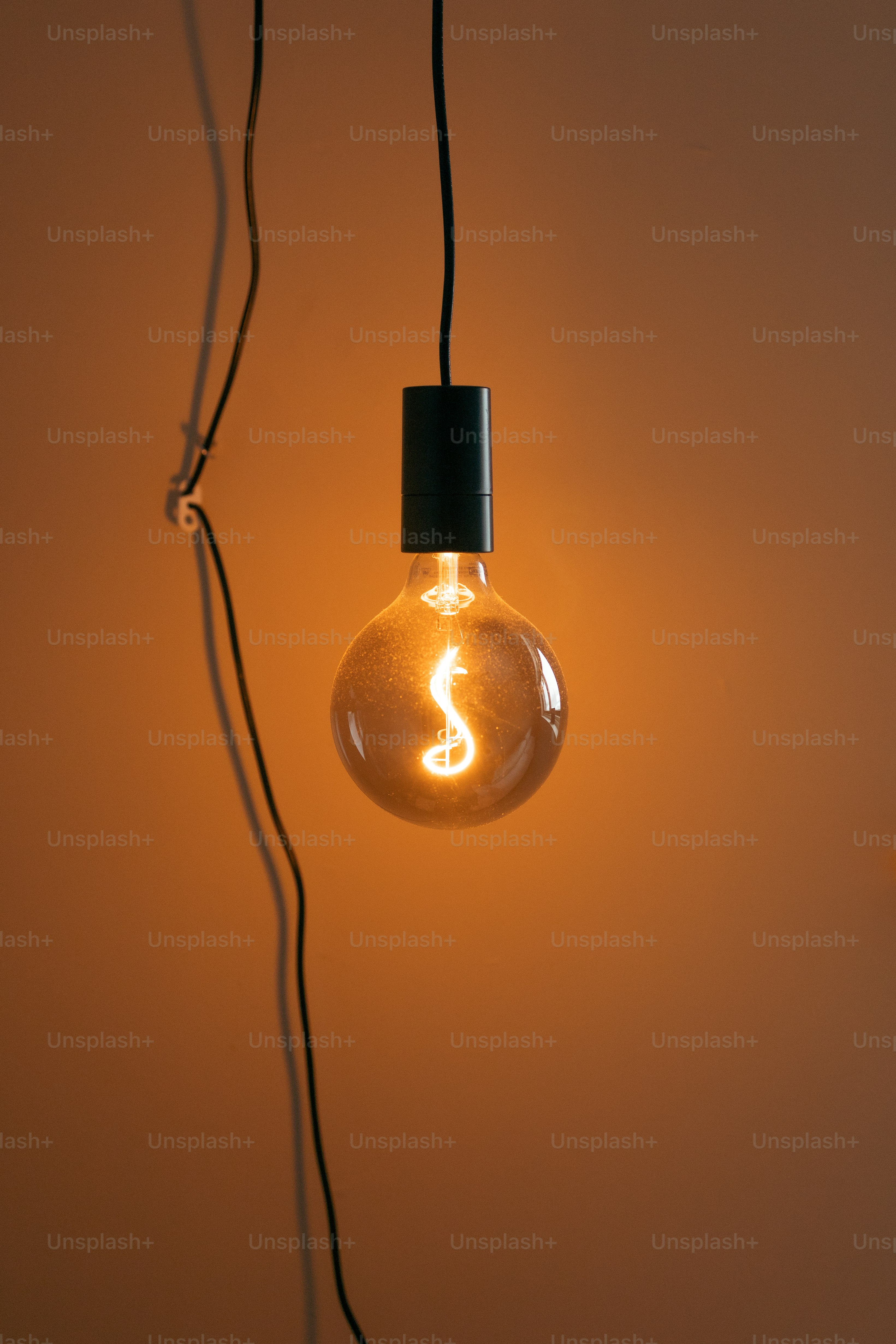 A light bulb with a black cord hanging from it photo Electricity
