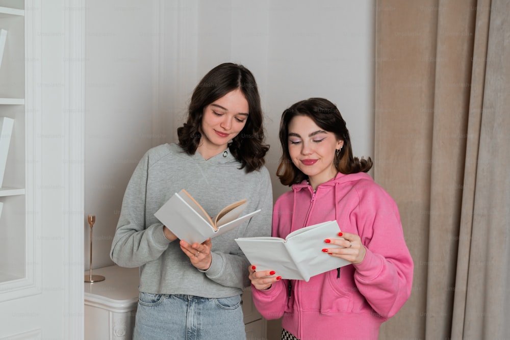 two women standing next to each other reading books