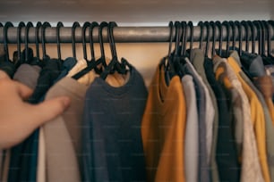 a person holding a rack of clothes in front of a rack of shirts