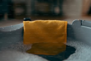 une serviette jaune assise dans une baignoire remplie d’eau