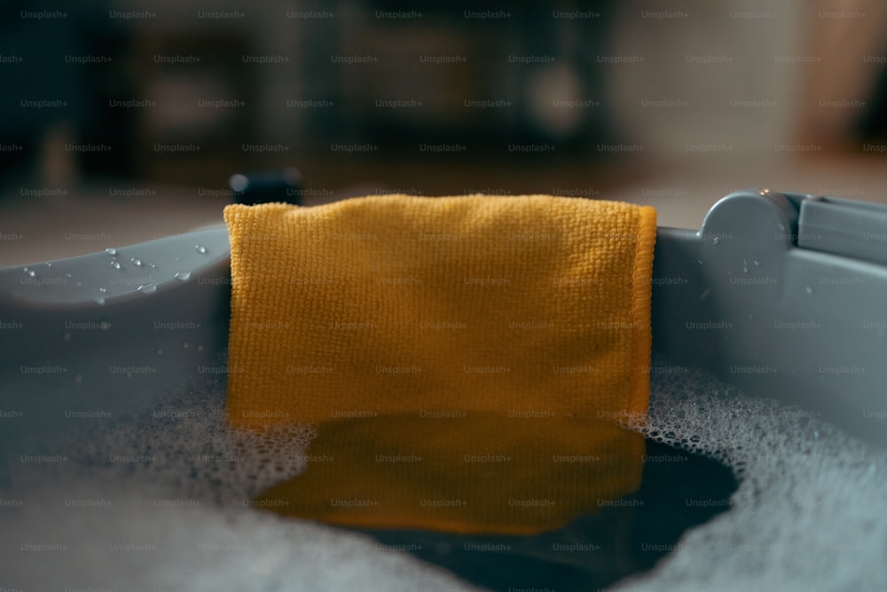 물이 채워진 욕조에 앉아있는 노란 수건