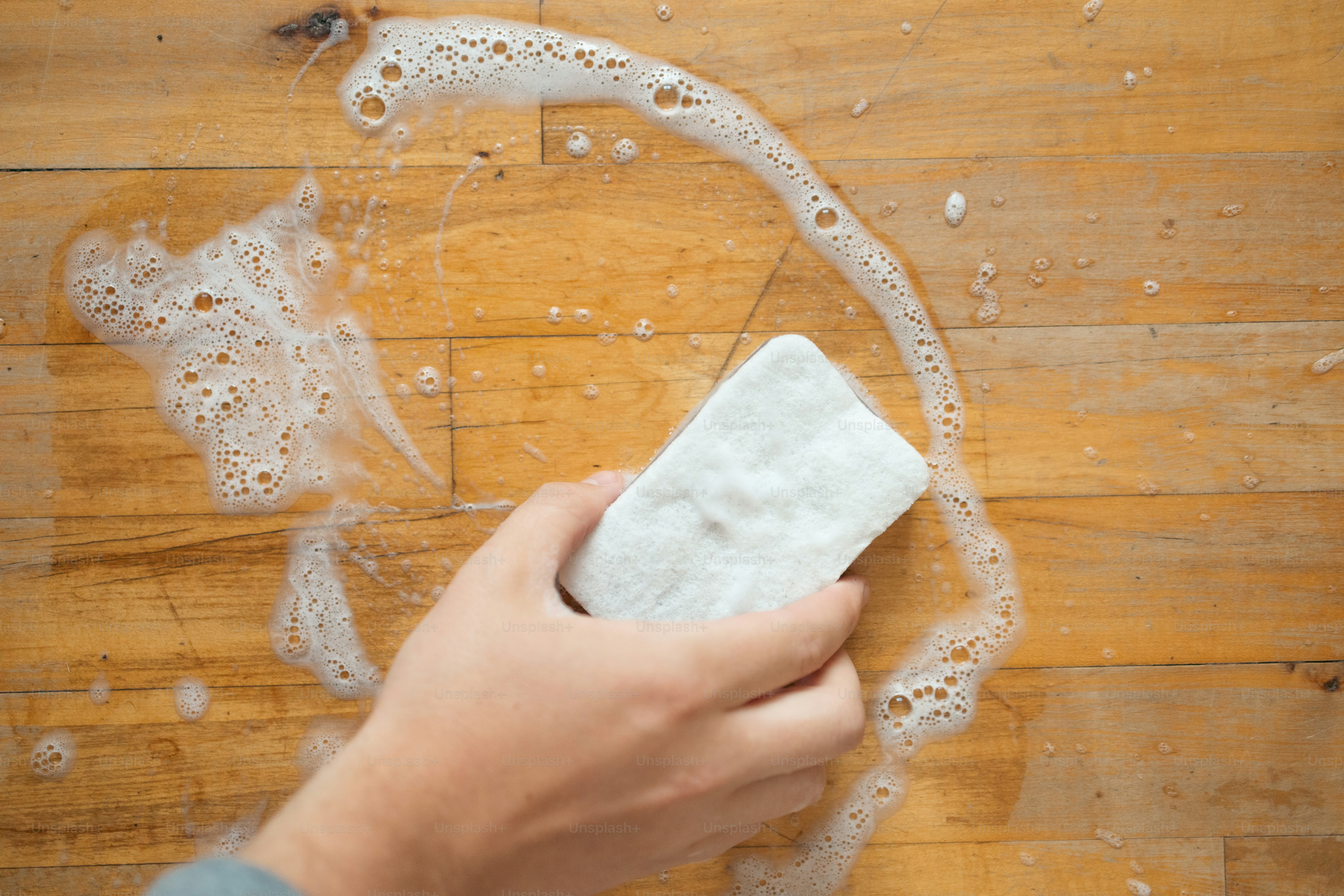 a person cleaning a wooden table with a cloth
