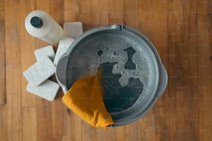 a bucket of water with a yellow cloth and a roll of toilet paper