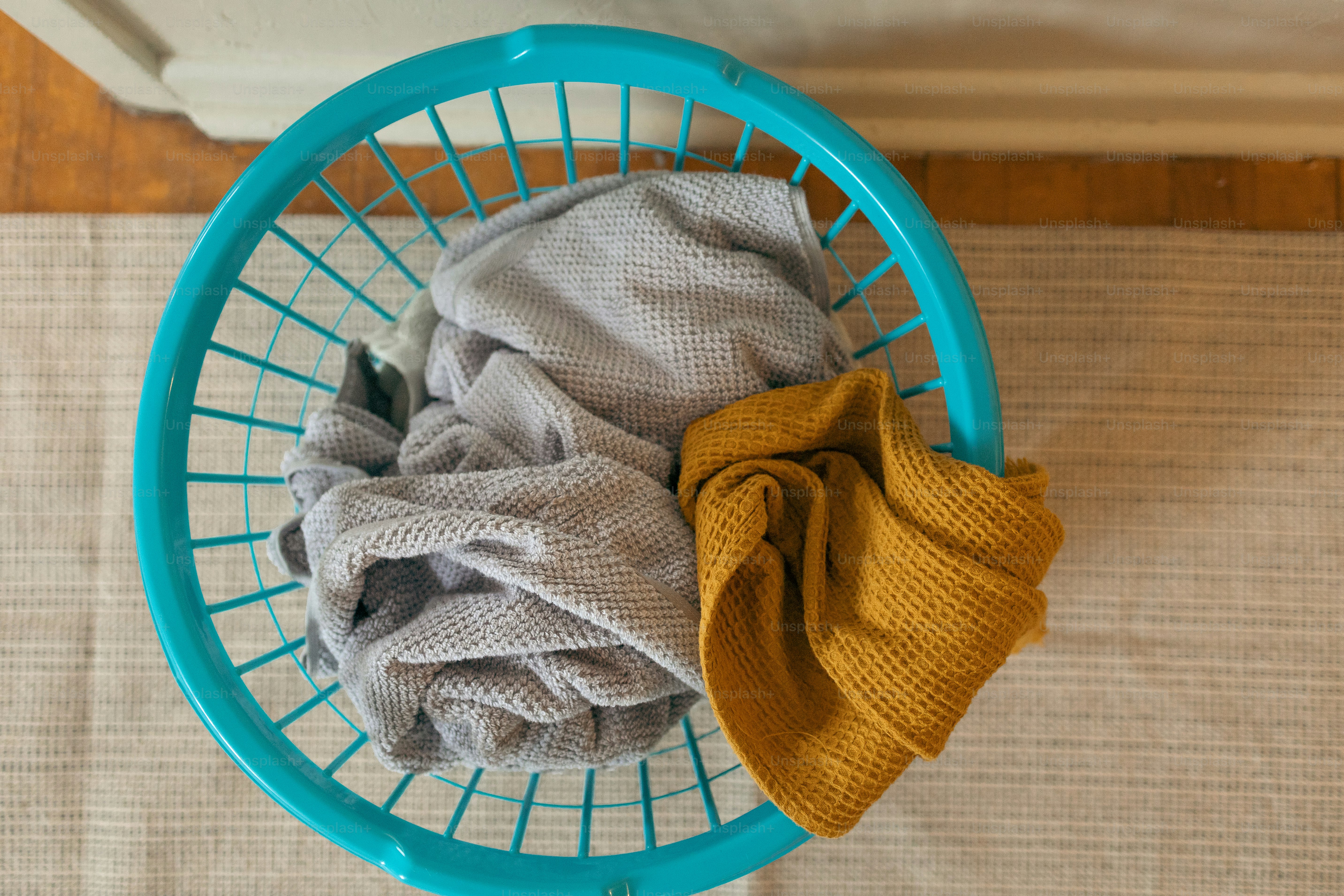 Wool dryer balls sitting in a laundry basket beside freshly dried clothes