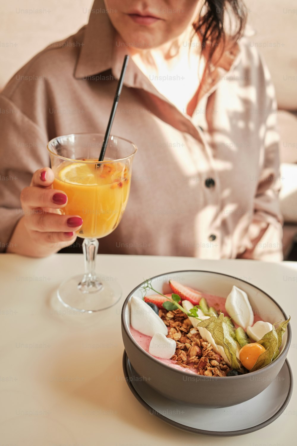 a woman sitting at a table with a bowl of food and a drink