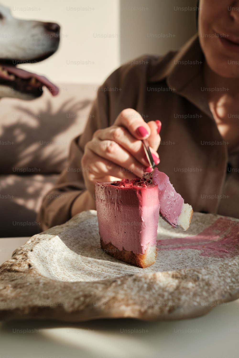 a woman holding a piece of cake in front of a dog