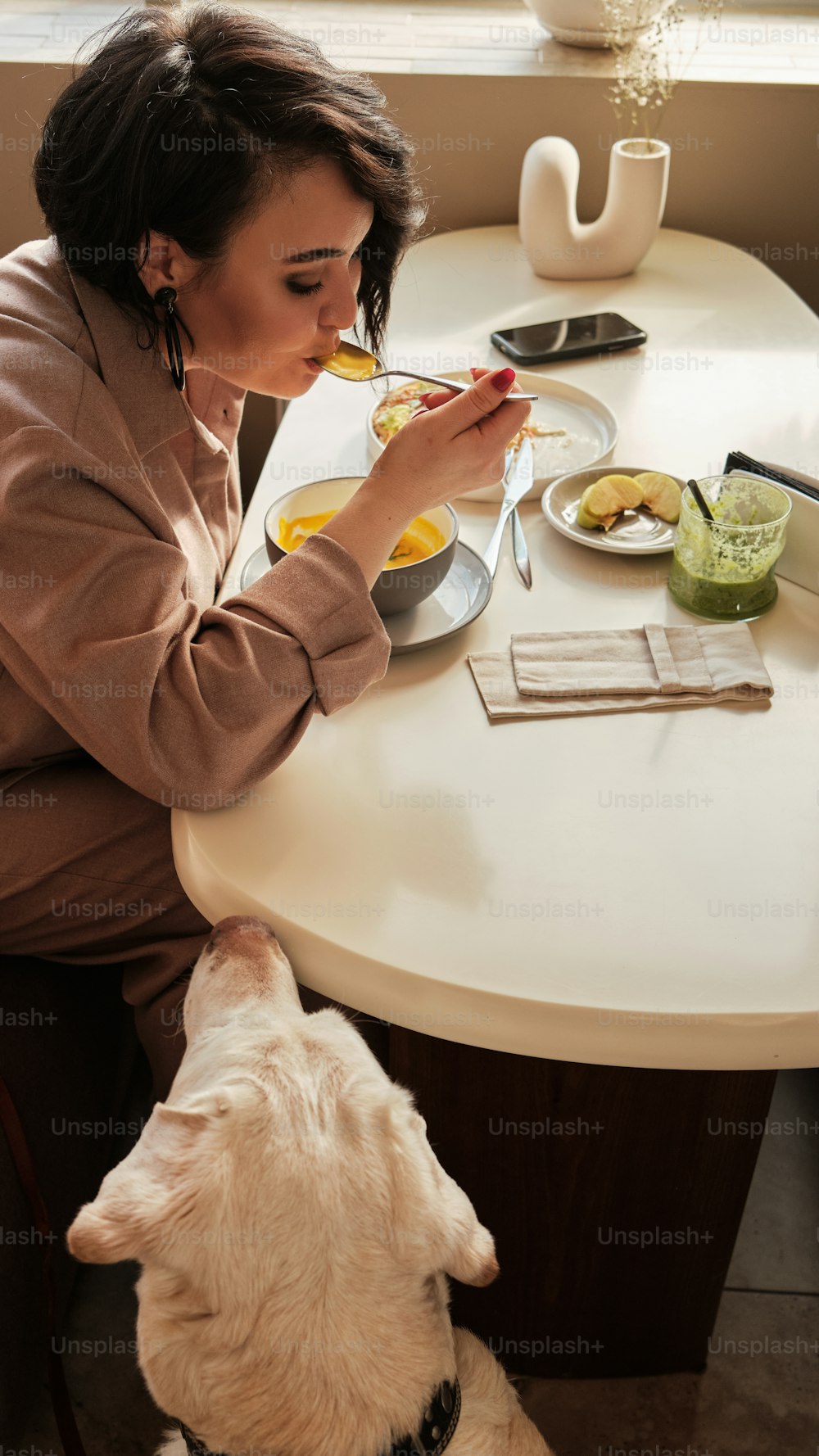 음식을 먹는 개와 함께 테이블에 앉아 �있는 여자