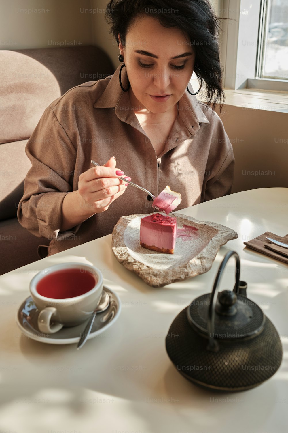 a woman sitting at a table eating a piece of cake