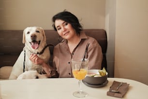 uma mulher sentada em uma mesa com um cão