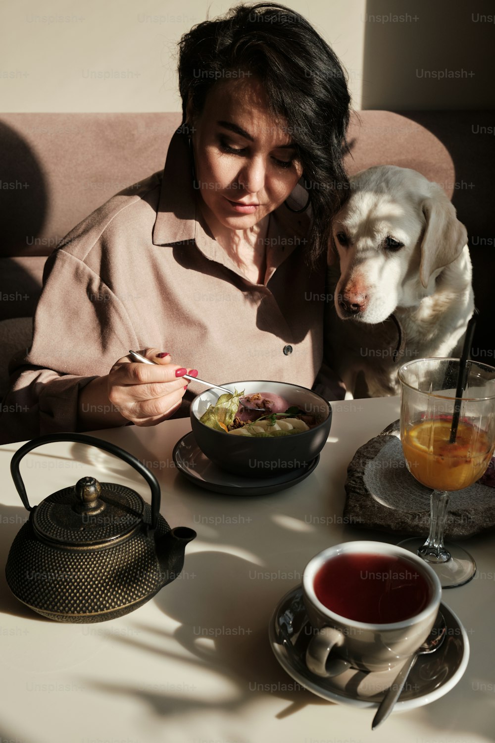 a woman sitting at a table with a dog next to her