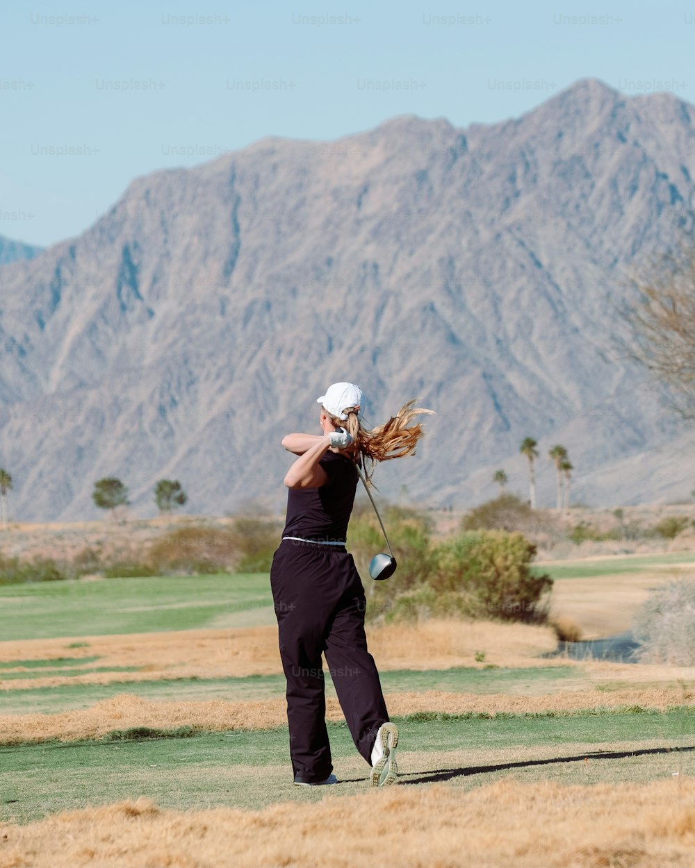 Una mujer balanceando un palo de golf en un campo de golf