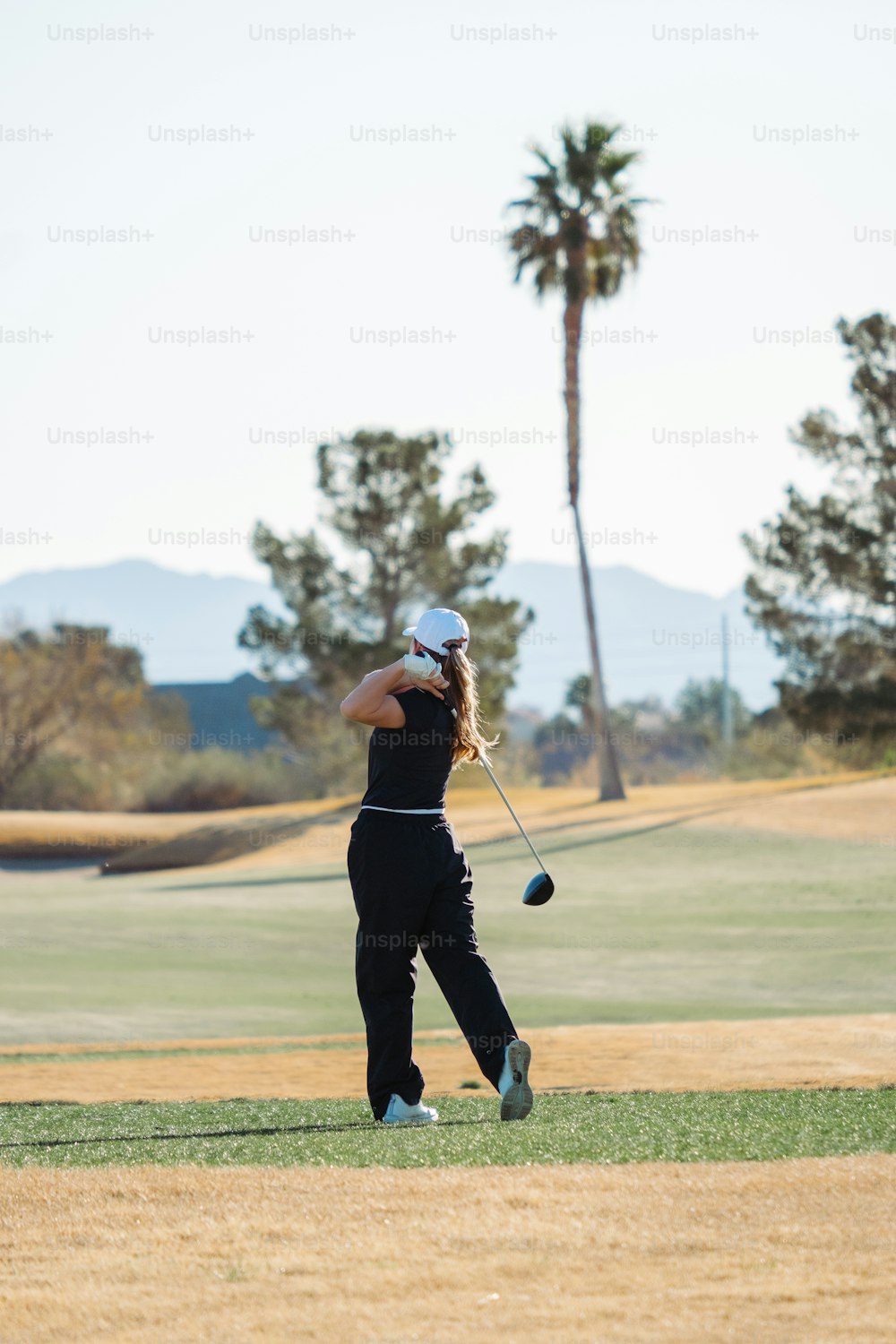 Una mujer balanceando un palo de golf en un campo de golf