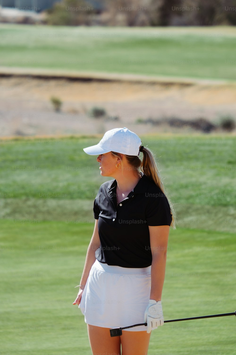 uma mulher em pé em um campo de golfe segurando um taco de golfe