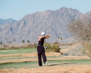 a woman swinging a golf club on a golf course