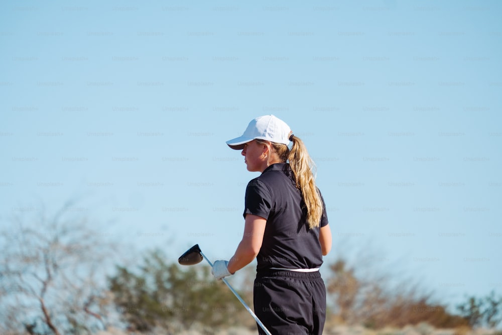 a woman holding a golf club on a golf course
